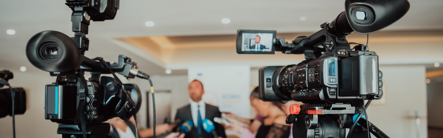Stock photo of multiple cameras and media professionals at a press conference, symbolizing Top of Mind PR’s expert media relations and public relations services.