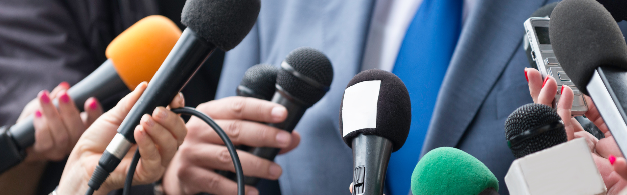 PR and media engagement in action, with microphones from various media outlets held by reporters. The image highlights Top of Mind PR's commitment to fostering strong media relationships, driving visibility, and amplifying brand messaging across traditional and digital channels.