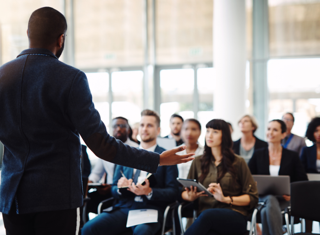 man speaking to group of people who are sitting