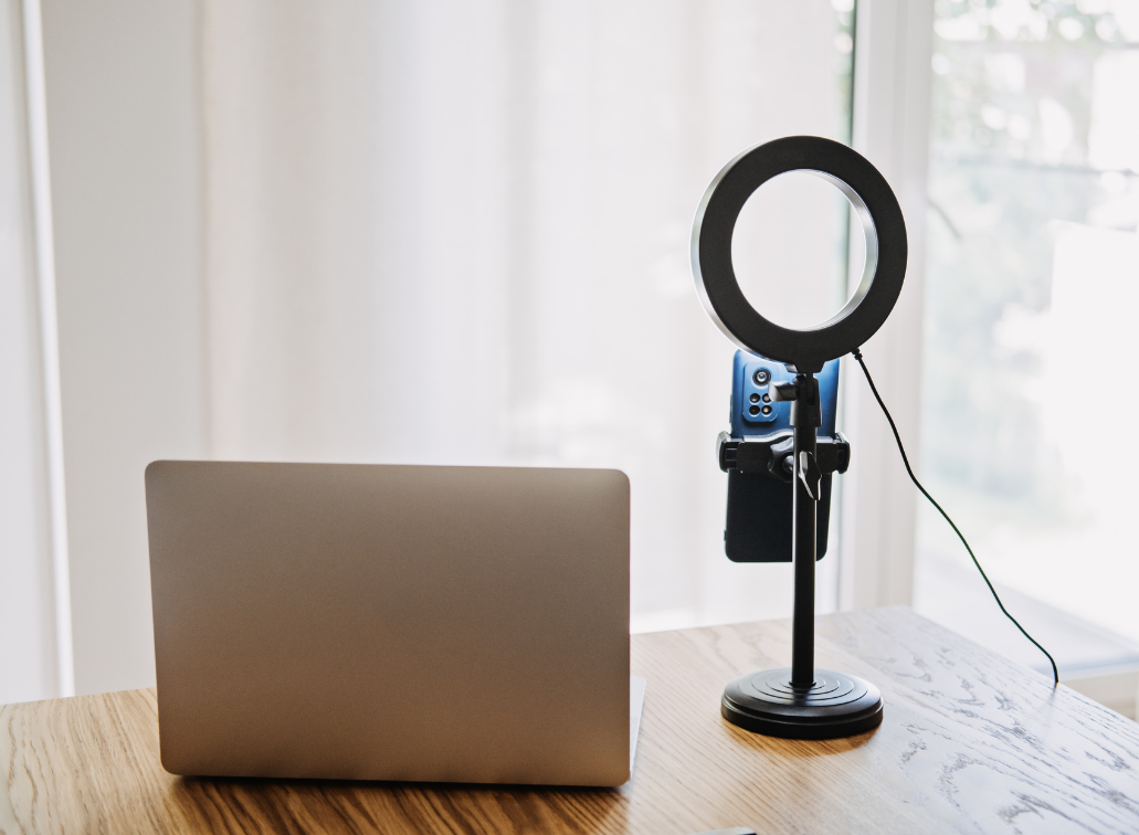 Image of a laptop and ring light on a table against a window