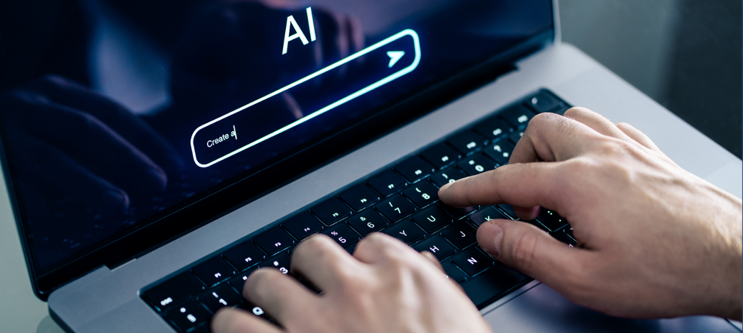 Hands typing on a laptop with an AI search interface displayed on the screen.
