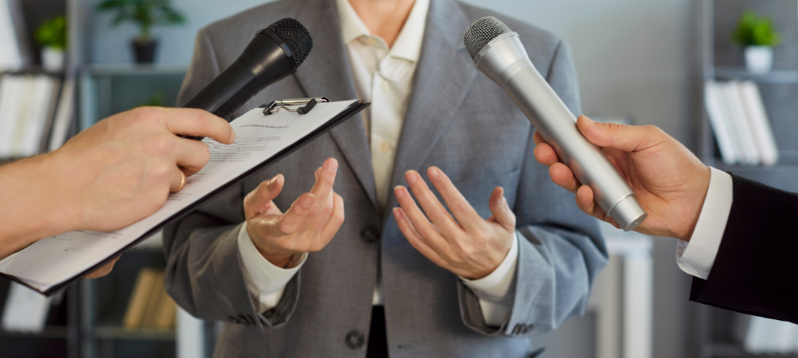 Business professional being interviewed by reporters with microphones, representing media coverage and public relations strategy