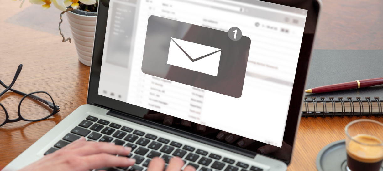 Person typing on a laptop displaying an email inbox interface with a large email notification icon on the screen, representing email marketing and digital communications.
